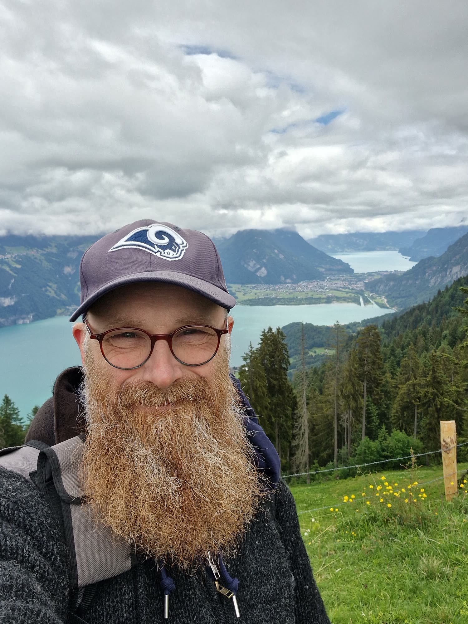 Thorsten Weber im Freien vor einem See mit Bergen im Hintergrund.
