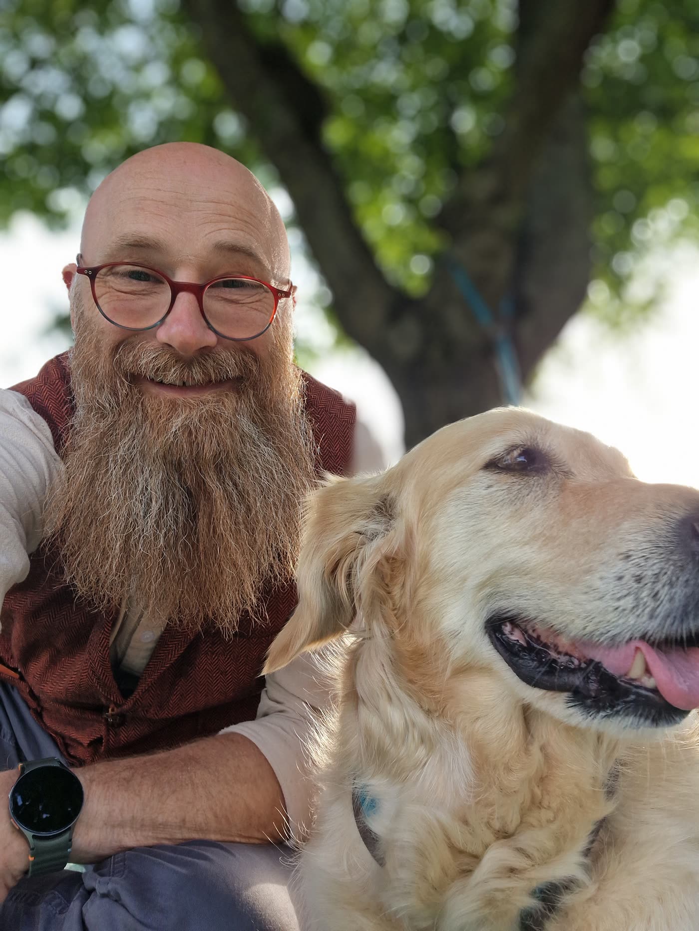 Thorsten Weber mit einem Golden Retriever unter einem Baum.